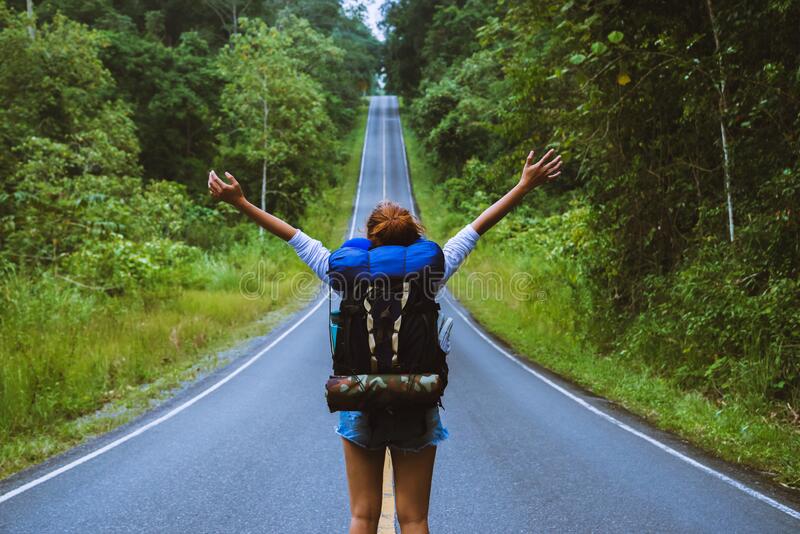 mujer viajera en libertad parada con los brazos levantados y disfrutando de una hermosa naturaleza un camino campo viaje mochila 169768871